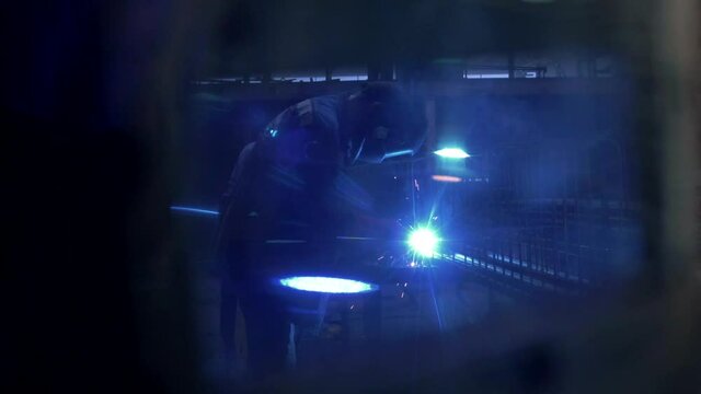 Professional welder is cooking metal. Reflection in the visor of the welder helmet. Sparks