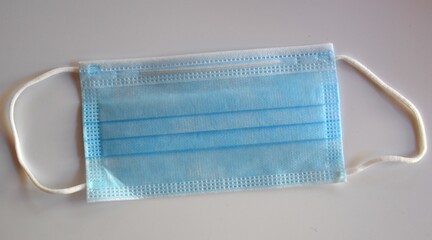 Blue surgical mask extended on gray background.