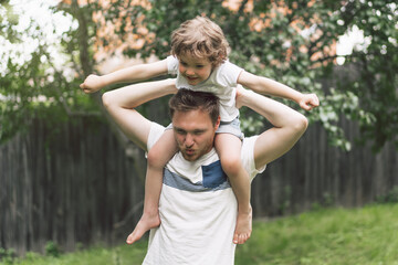 Fototapeta premium Father and his son playing and hugging in outdoors. Concept of Father's day. 