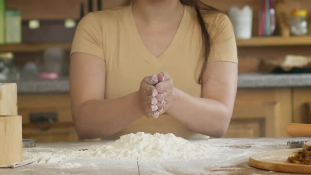 slow motion close-up view of woman's hands clapping with flour while cooking dough at kitchen baking pastry at home, positive housewife cooking alone preparing pie cake or handmade cookies DIY bakery