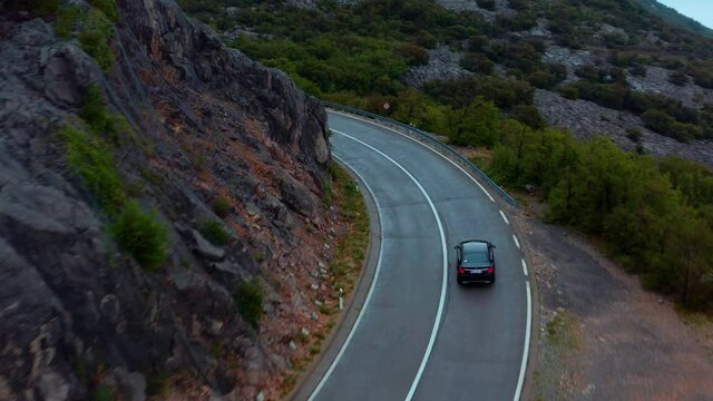 Black car driving through winding road in the mountains of Velebit, Croatia 