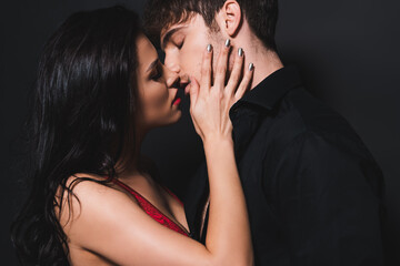 sexy couple with closed eyes kissing on black