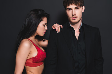 sexy woman in red and lace bra touching handsome man on black