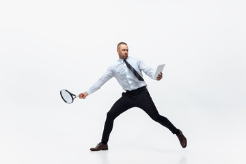 Time for movement. Man in office clothes plays tennis isolated on white studio background. Businessman training in motion, action. Unusual look for sportsman, new activity. Sport, healthy lifestyle.