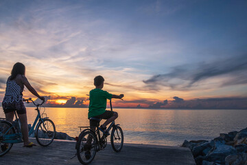 Fototapeta premium Mother and child ride a bicycle on the beach happily.