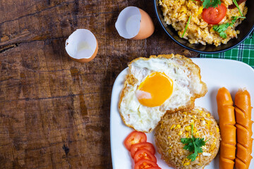.American fried rice served with fried eggs and sausages on the table