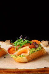 Selection of tasty bruschetta or canapes with salmon closeup. salmon tapas with guacamole and topped microgreen