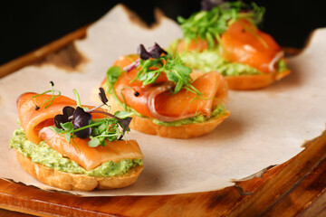 Selection of tasty bruschetta or canapes with salmon closeup. salmon tapas with guacamole and topped microgreen