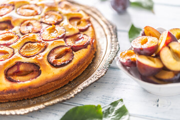 Homemade plum cake in vintage plate on wooden table. Plums pie with sugar powder