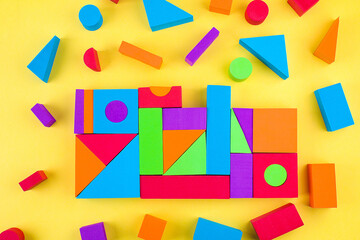 Kids designer of multi-colored volumetric 3d geometric shapes on yellow background. Logical educational game.