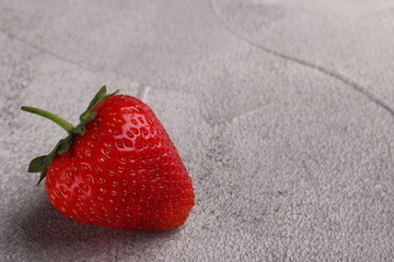 one strawberry closeup on light concrete background