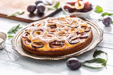 Homemade plum cake in vintage plate on wooden table. Plums pie with sugar powder