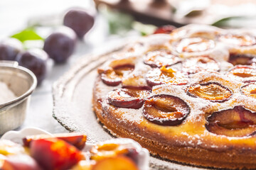 Homemade plum cake in vintage plate on wooden table. Plums pie with sugar powder