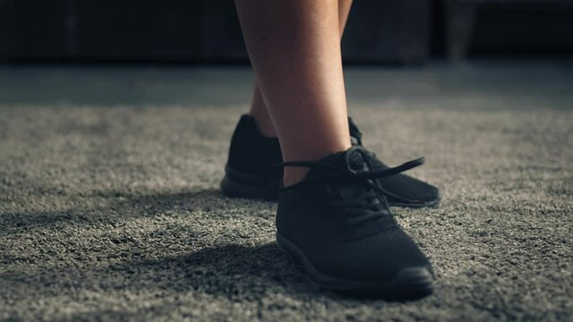 woman walking on carpet and stop in front of camera. Detail of Woman feet wearing sport shoes walking and stopping in front of camera. Home indoor close up.