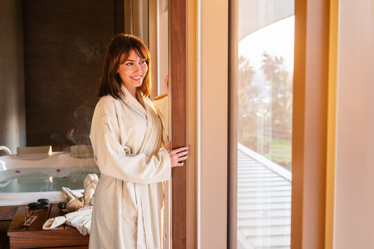beautiful woman is looking out from window while waiting for massage at spa center.
