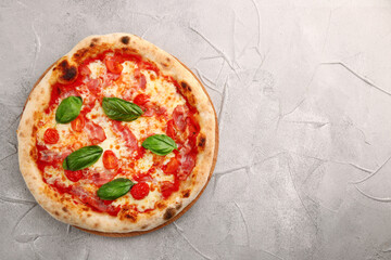 pizza with bacon, cherry tomatoes and basil on light concrete or stone table top view