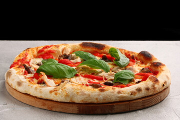 pizza with mushrooms, tomato and chicken closeup pizza with mushrooms and chicken on light concrete or stone table and black background for copy space