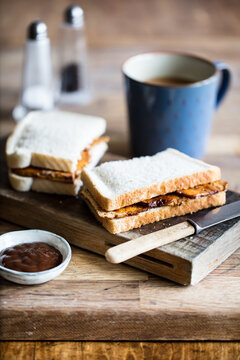 Vegan bacon style tofu sandwich with a mug on tea on a rustic oak chopping board