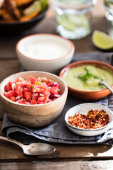 Selection of Mexican style dips, salsa and guacamole on rustic wooden table