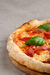 pizza prosciutto with basil and Mozzarella closeup on light concrete or stone background