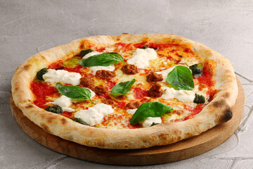strachatella pizza closeup on light concrete or stone background. pizza with meat, pesto, tomatoes and stracciatella cheese