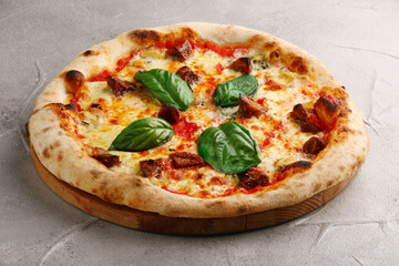 pizza with mushrooms, tomato and basil close up on light concrete or stone table and black background for copy space