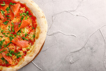 salmon pizza with green close up on gray concrete or stone table top view.