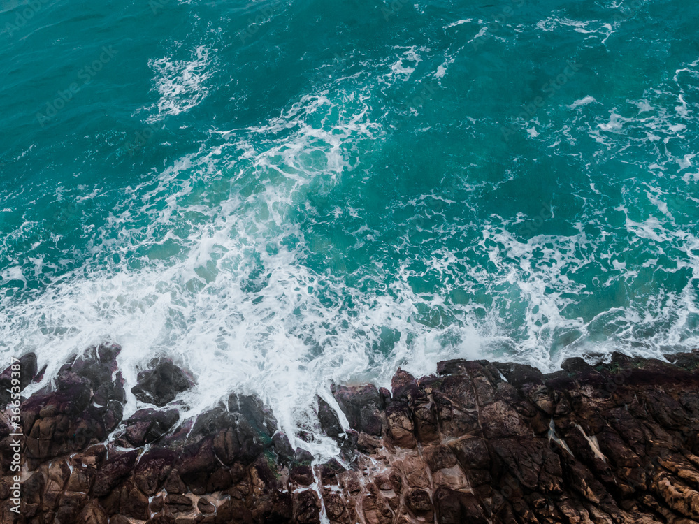 Wall mural aerial view of crashing waves on rocks.