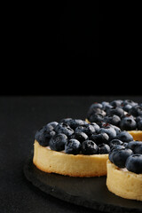 blueberry tart on dark background . set of mini tart cake with blueberries