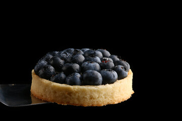 blueberry tart close up on isolated black background with copy space