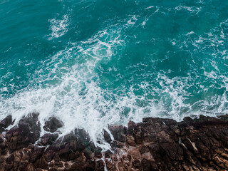 Aerial view of crashing waves on rocks.