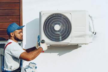 Fototapeta Repairman in uniform installing the outside unit of air conditioner obraz