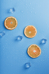 Slices of fresh orange on a blue background with ice.
