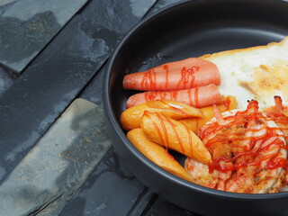 Breakfast served with Bologna sausage, Sausage, bread and egg in black dish on black background, High nutrition and power in the morning, Homemade breakfast at home.