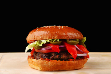 tasty burger with beef close up on wood and black isolated background for copy space. Homemade hamburger or burger with fresh vegetables and sauce