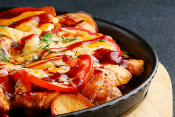 frying pan with potatoes meat and tomatoes on black concrete background. mexican food concept. potatoes fried in a pan