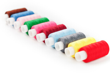 Fototapeta na wymiar Sewing threads of different colors on reels on a white background. Free space, close-up. Isolate