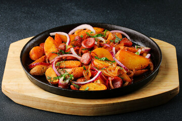 frying pan with potatoes meat and onion close up on black concrete background. mexican food concept. potatoes fried in a pan