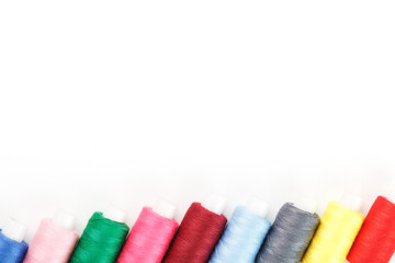 Sewing threads of different colors on reels on a white background. Free space, close-up. Isolate
