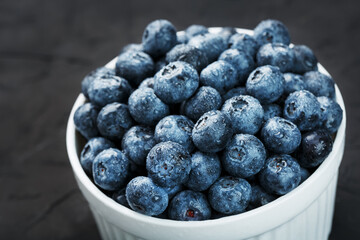 Fototapeta na wymiar Organic blueberries in a white Cup on a black Board.