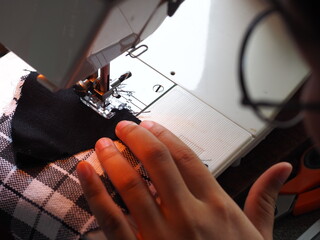 Tailoring Process - Women's hands behind her sewing machine, Work by the light of the built-in hardware lamp. Steel needle with looper and presser foot close-up.