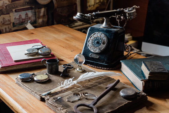 antiques office desk with accessories: old telephone, books, globe, notes, ink pen, vintage glasses and for hours. The picture conveys the atmosphere of antiquity - past years