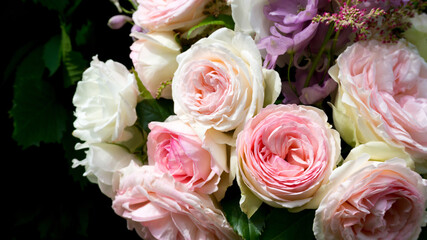 A bouquet of delicate pink roses close-up on a black background with space for text. Fresh roses in a wedding bouquet. Romantic card for congratulations on the wedding, anniversary, Valentine's Day.