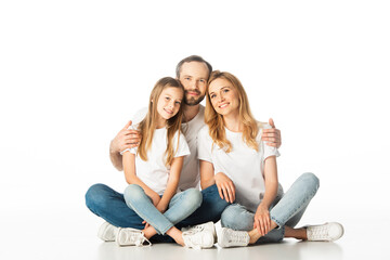 Fototapeta na wymiar happy family sitting on floor with crossed legs and embracing isolated on white