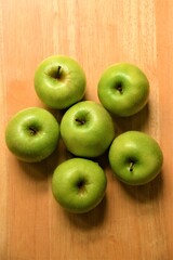 Six ripe green Granny Smith apples on wooden background