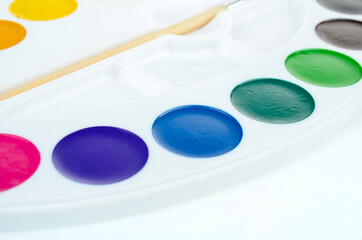 Obraz na płótnie Canvas A set of close-up watercolors isolated on a white background. A palette of bright colors for drawing. Creative development for children and school children. Office supplies for September 1
