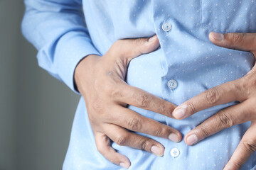 man touching stomach suffering pain close up.