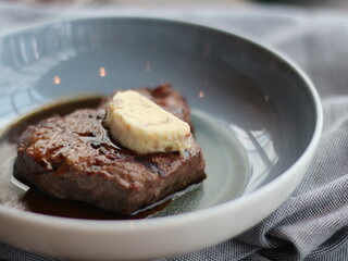 Beef Steak on a Grey Plate and Grey Napkin. Beef Steak with Melting Butter on top.