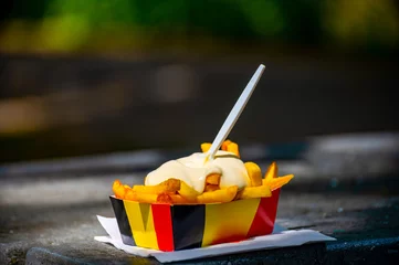 Gardinen Paper box in colors of Belgian flag with fried potato frit chips and mayonnaise sauсe. © barmalini