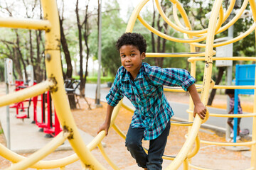 African American young boy smiling and playing at the playground in the city park, looking at...